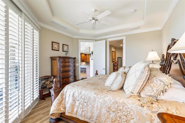 bedroom featuring ceiling fan, light hardwood / wood-style floors, crown molding, and a tray ceiling