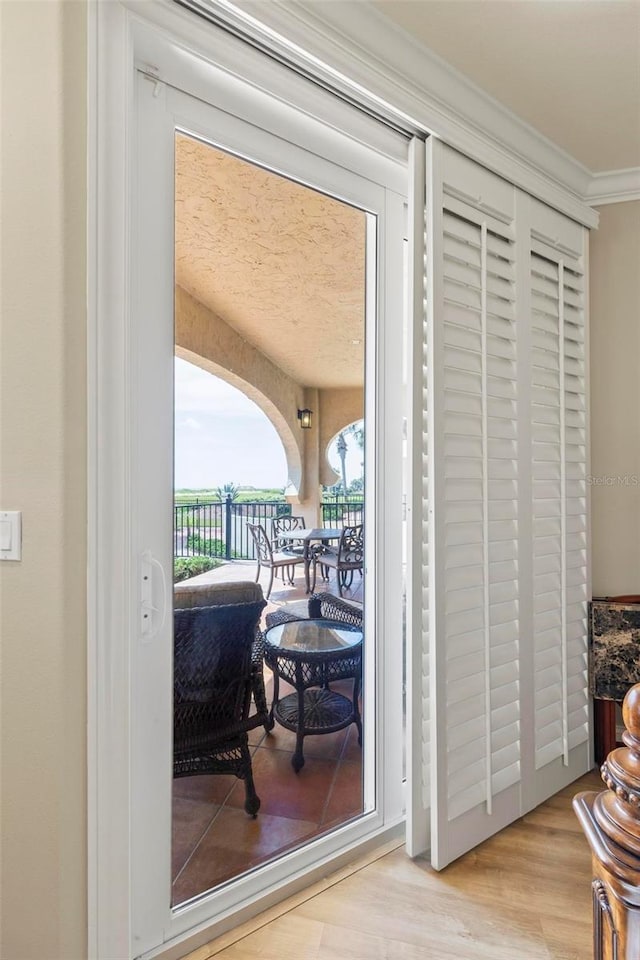 doorway with light hardwood / wood-style floors and ornamental molding