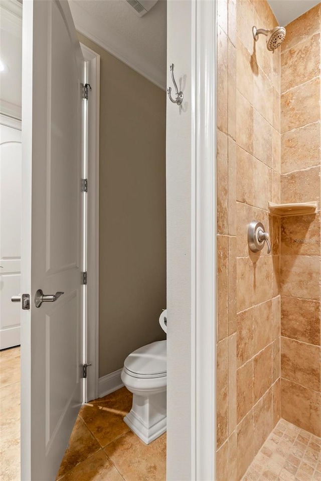 bathroom featuring a tile shower, tile patterned floors, and toilet