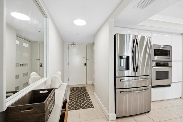 interior space featuring white cabinets, light tile patterned floors, stainless steel appliances, and ornamental molding