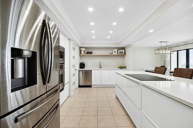 kitchen with appliances with stainless steel finishes, sink, light tile patterned floors, white cabinetry, and hanging light fixtures