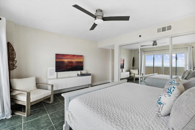 bedroom with ceiling fan, dark tile patterned floors, and a closet