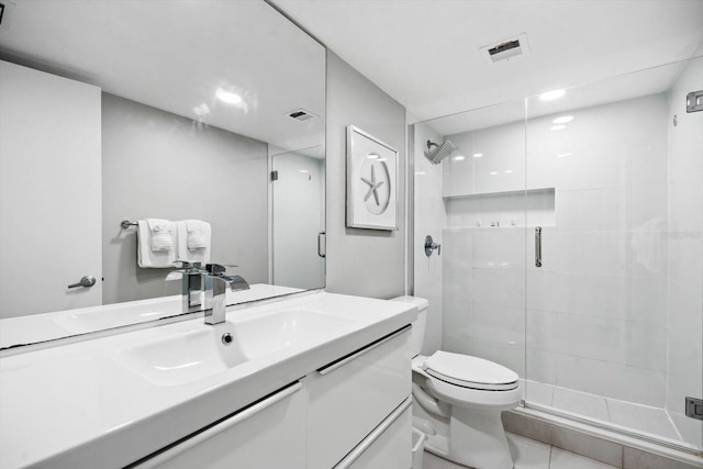 bathroom with tile patterned flooring, a shower with door, vanity, and toilet