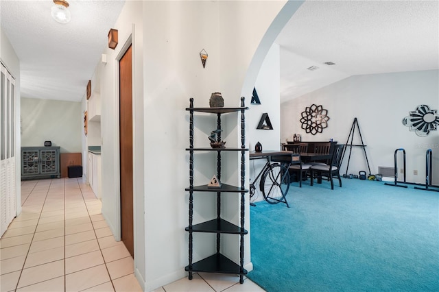 hallway featuring light tile patterned floors and vaulted ceiling