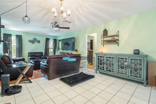 living room featuring light tile patterned floors, ceiling fan with notable chandelier, and a textured ceiling