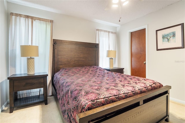 bedroom with ceiling fan, light colored carpet, and a textured ceiling