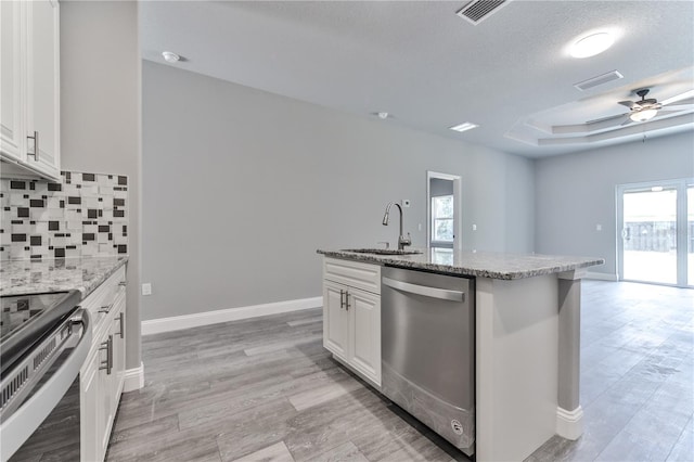 kitchen with stainless steel appliances, white cabinetry, sink, and a tray ceiling