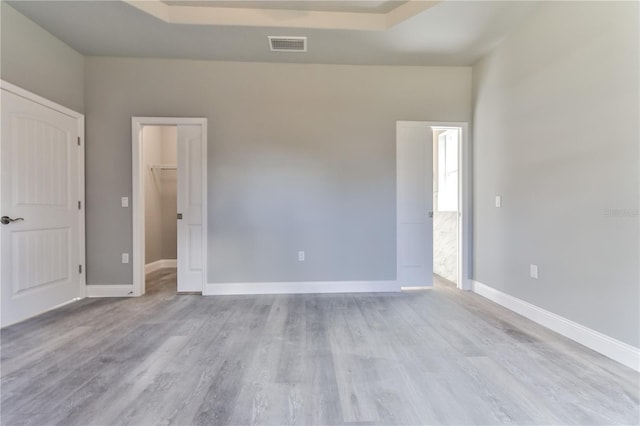 unfurnished room with a tray ceiling and light hardwood / wood-style flooring