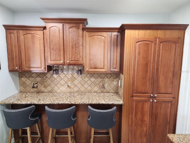 10611 SW 164th St, Miami, FL 33157 - kitchen with decorative backsplash, a kitchen breakfast bar, light stone countertops, and brown cabinetry