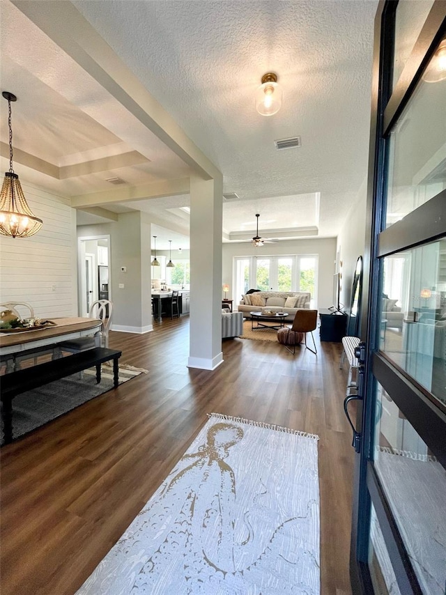 interior space featuring a textured ceiling, a raised ceiling, and dark wood-type flooring