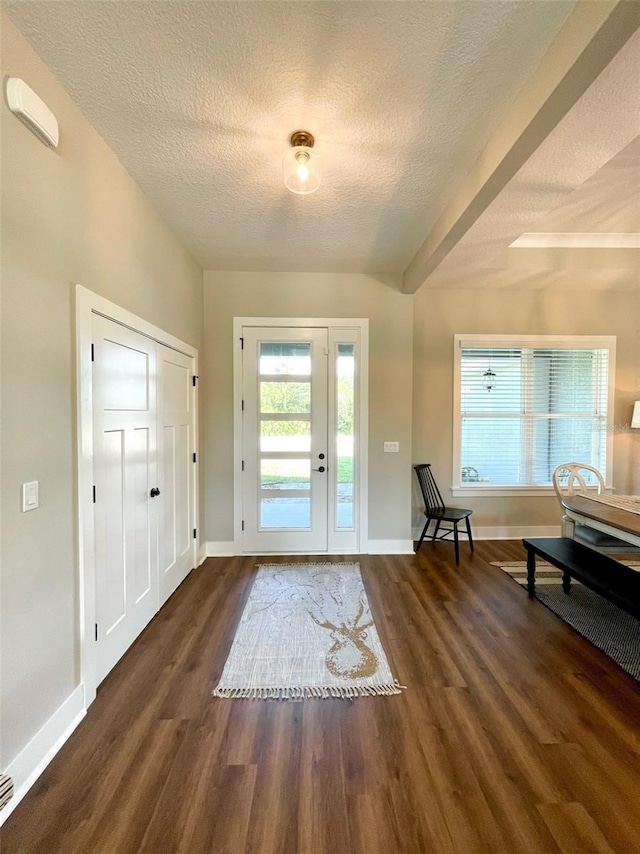 entryway with beamed ceiling, a textured ceiling, and dark hardwood / wood-style flooring