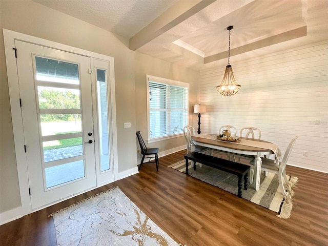 dining room with a chandelier, a textured ceiling, dark hardwood / wood-style floors, and a raised ceiling