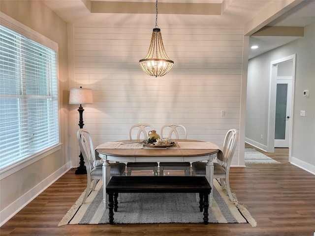 dining area with wood walls, a healthy amount of sunlight, dark hardwood / wood-style flooring, and an inviting chandelier