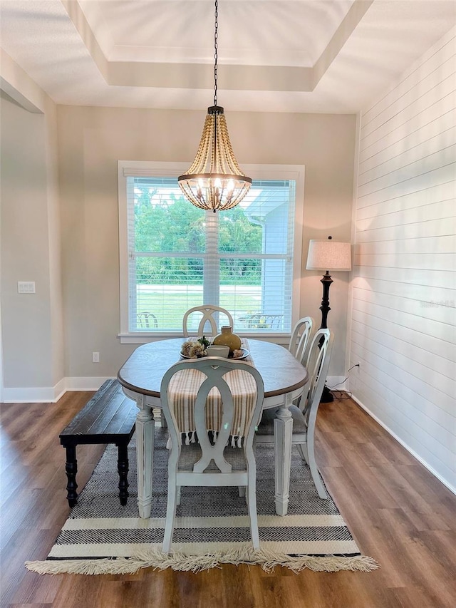 dining area featuring a tray ceiling, dark wood-type flooring, and a notable chandelier