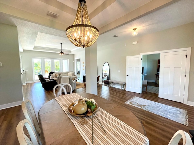 dining space featuring dark hardwood / wood-style floors, a raised ceiling, a textured ceiling, and ceiling fan with notable chandelier