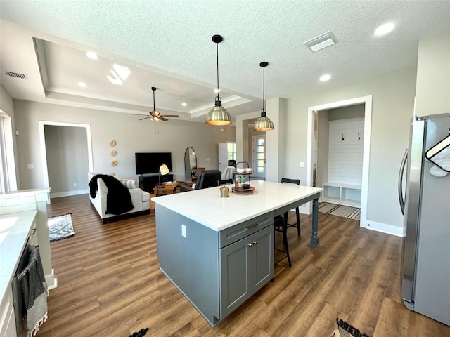 kitchen featuring pendant lighting, dark hardwood / wood-style floors, stainless steel fridge, gray cabinets, and a kitchen island