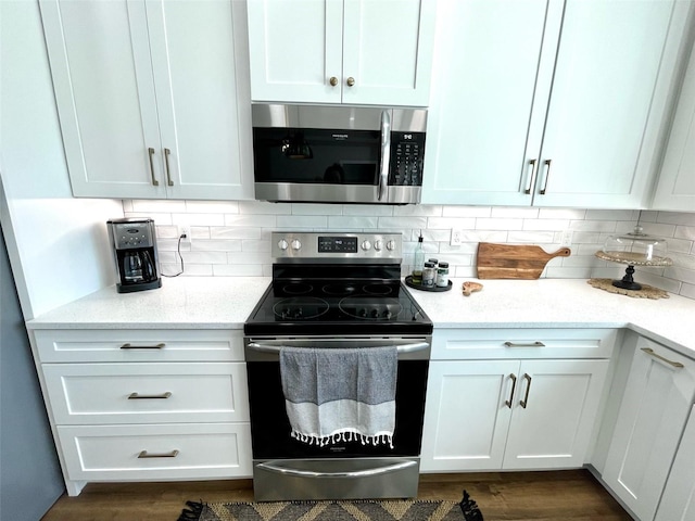 kitchen featuring light stone countertops, dark wood-type flooring, tasteful backsplash, white cabinets, and appliances with stainless steel finishes