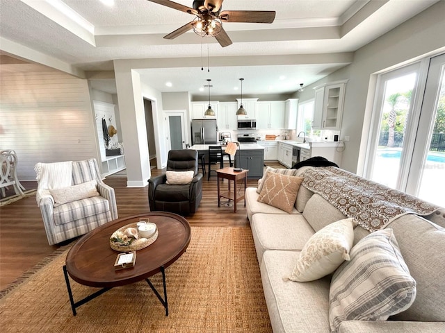 living room featuring hardwood / wood-style floors, a tray ceiling, ceiling fan, and sink