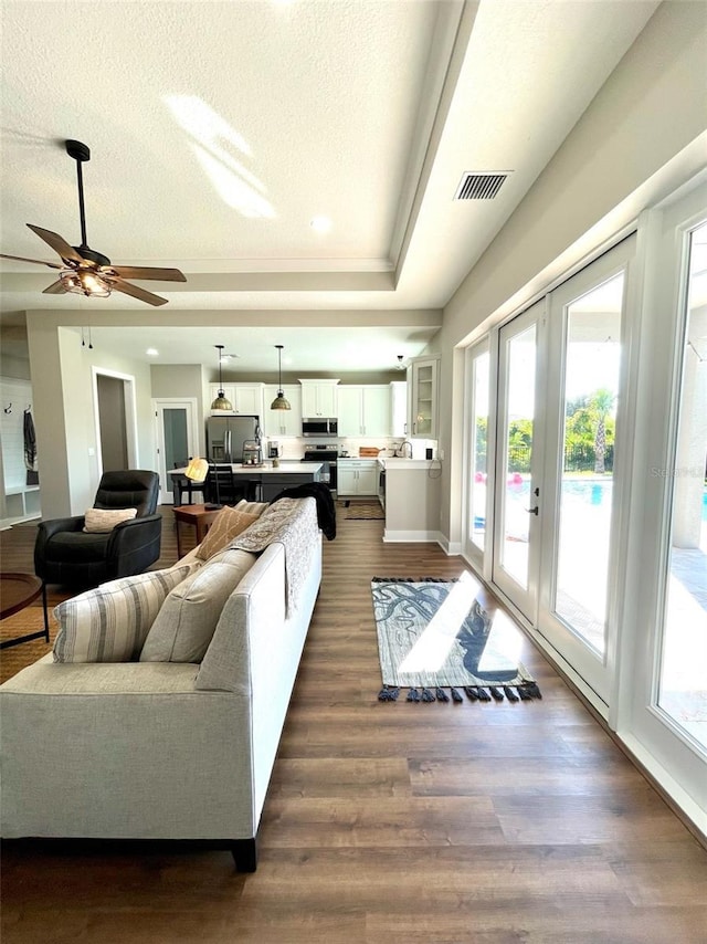 living room with a textured ceiling, dark wood-type flooring, and french doors