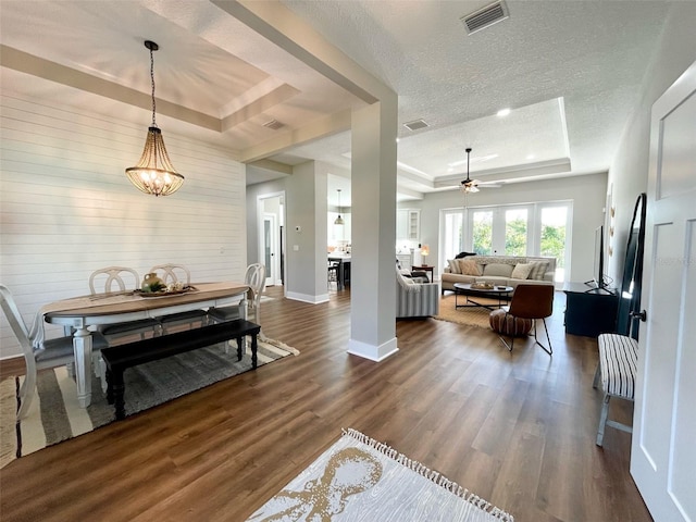 interior space with a textured ceiling, dark wood-type flooring, and a tray ceiling