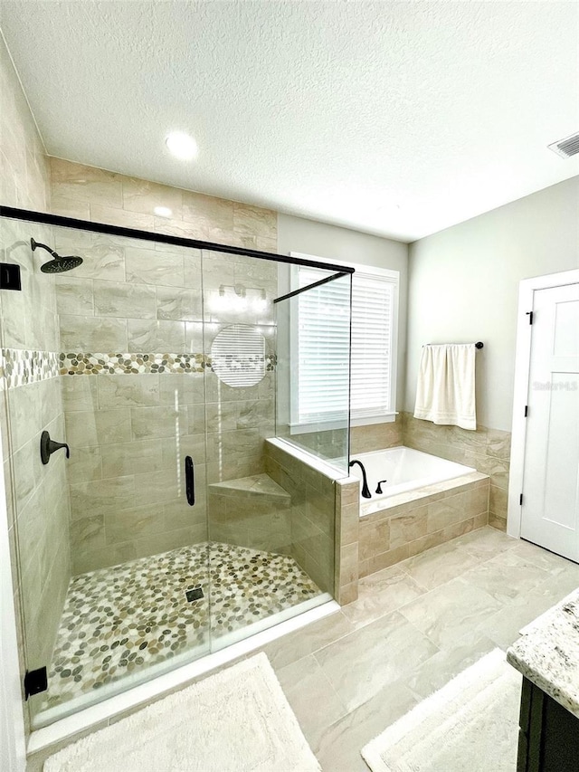 bathroom with vanity, shower with separate bathtub, and a textured ceiling