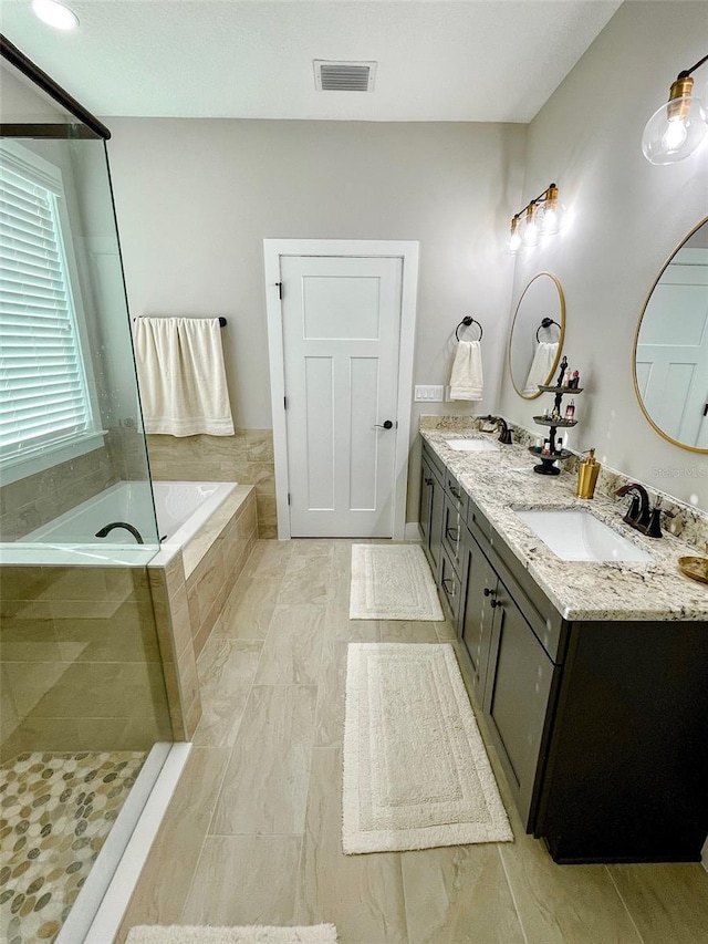 bathroom with vanity and tiled bath