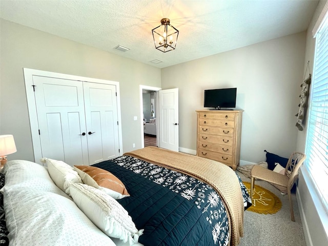 bedroom with a textured ceiling, a closet, multiple windows, and a notable chandelier