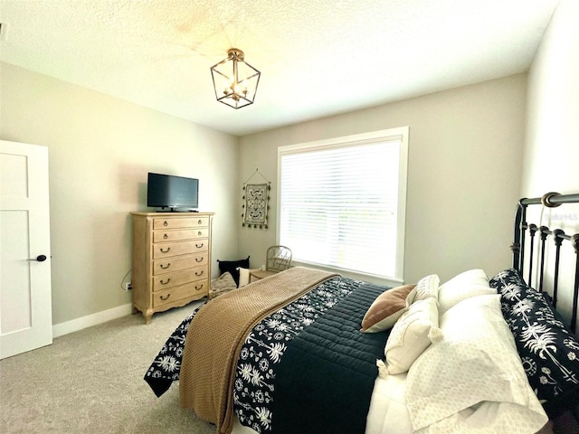 bedroom featuring carpet, a textured ceiling, and an inviting chandelier