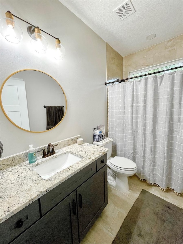 bathroom with vanity, tile patterned floors, toilet, a textured ceiling, and walk in shower