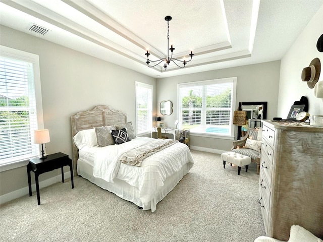 bedroom with light carpet, a chandelier, and a tray ceiling