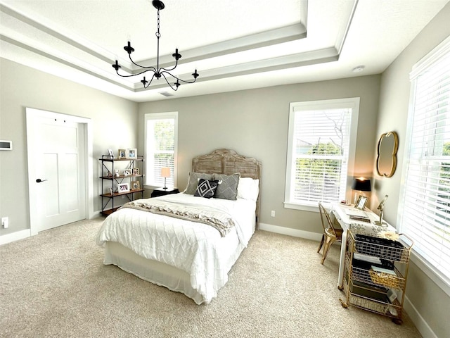 carpeted bedroom with a tray ceiling and an inviting chandelier