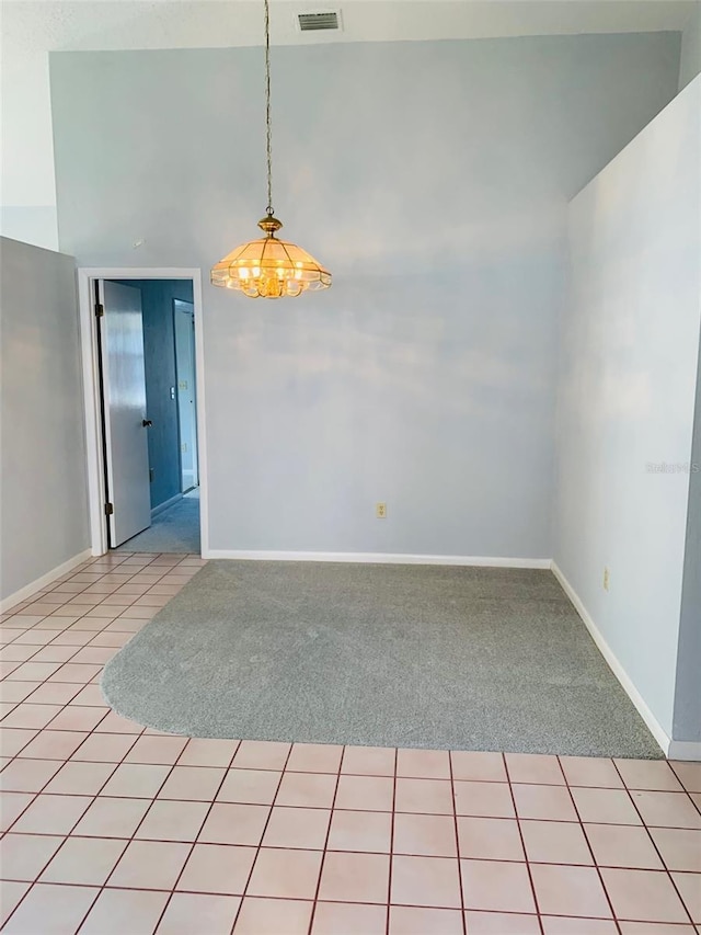 spare room featuring light carpet, light tile patterned flooring, visible vents, and baseboards