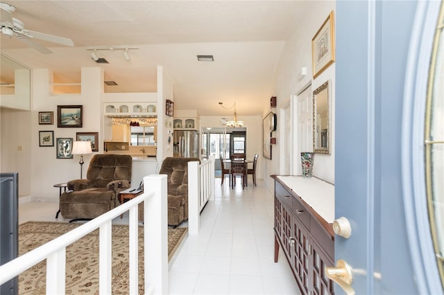 hallway with visible vents, rail lighting, an inviting chandelier, light tile patterned flooring, and a textured ceiling