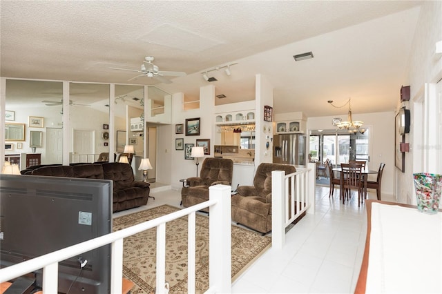 living room featuring a textured ceiling, light tile patterned floors, lofted ceiling, rail lighting, and ceiling fan with notable chandelier