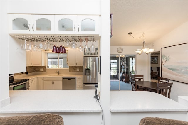 kitchen with a sink, stainless steel appliances, light countertops, lofted ceiling, and a chandelier