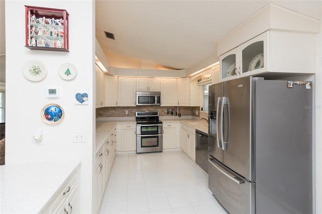 kitchen featuring light countertops, vaulted ceiling, decorative backsplash, appliances with stainless steel finishes, and a sink