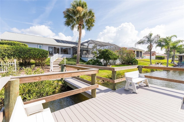 view of dock featuring glass enclosure, a water view, a lawn, and a residential view