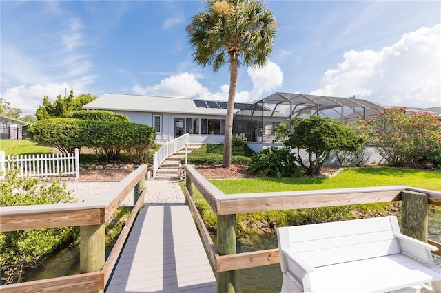 rear view of house with glass enclosure, a yard, and a water view