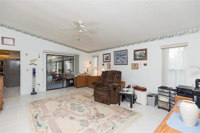 living room featuring a textured ceiling, vaulted ceiling, tile patterned flooring, and ceiling fan