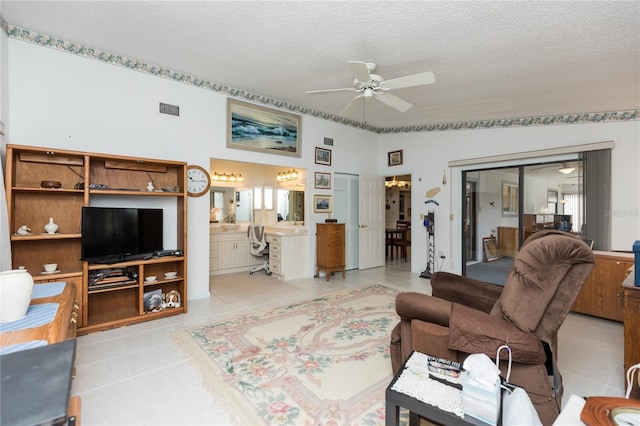 living room with light tile patterned floors, a ceiling fan, visible vents, lofted ceiling, and a textured ceiling