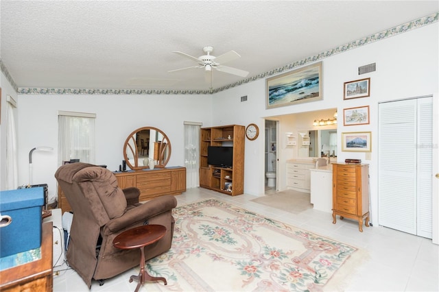 living room with a textured ceiling, ceiling fan, and light tile patterned floors