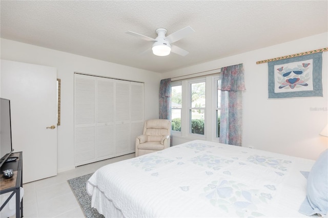 tiled bedroom featuring ceiling fan, a closet, and a textured ceiling