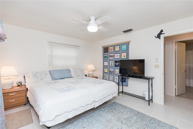 bedroom with tile patterned flooring, a ceiling fan, visible vents, and a textured ceiling