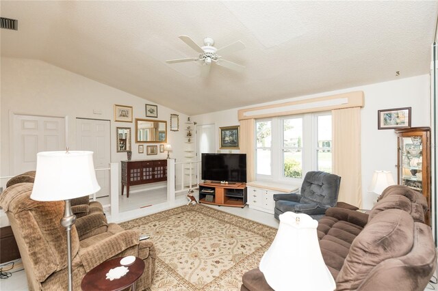 living room with ceiling fan, vaulted ceiling, and a textured ceiling