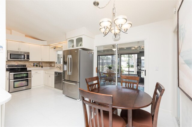 dining room featuring lofted ceiling, sink, and ceiling fan with notable chandelier