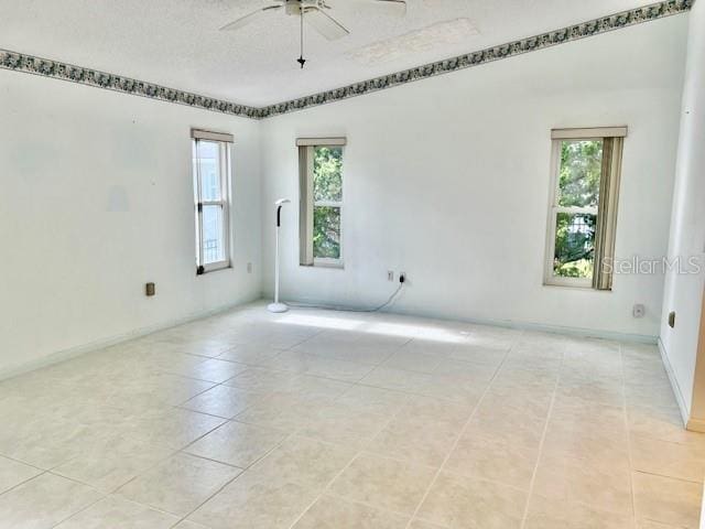 spare room featuring light tile patterned floors, a textured ceiling, and a ceiling fan