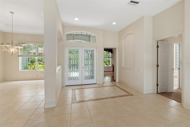 tiled foyer entrance featuring french doors and an inviting chandelier