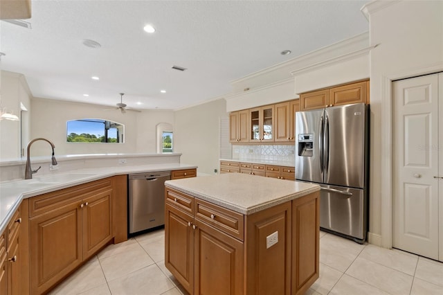 kitchen featuring appliances with stainless steel finishes, sink, decorative backsplash, a center island, and light tile patterned floors