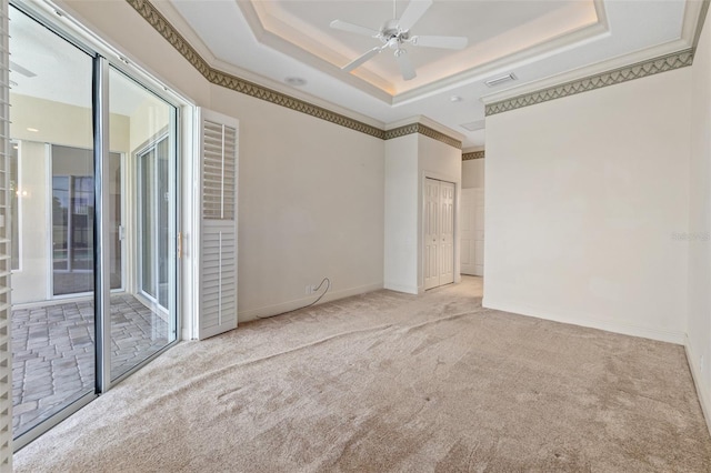 unfurnished room with ceiling fan, light colored carpet, and a tray ceiling