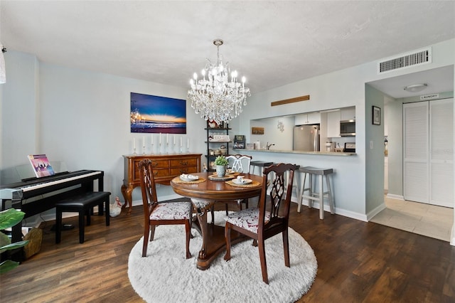 dining area with wood-type flooring and a chandelier